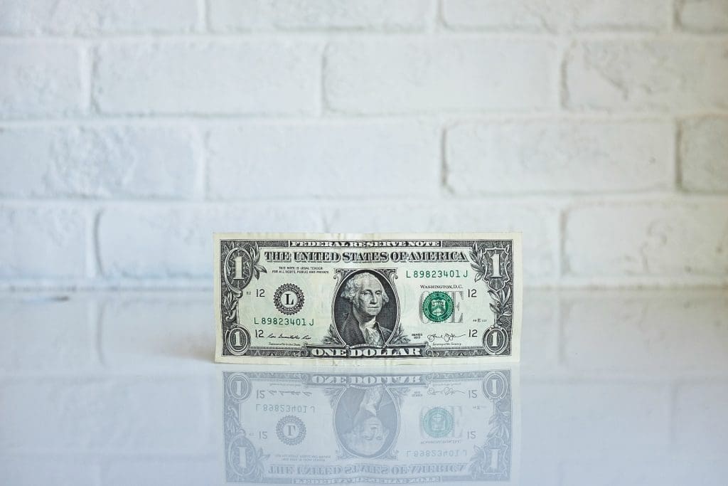 A $1 bill against a white tiled background